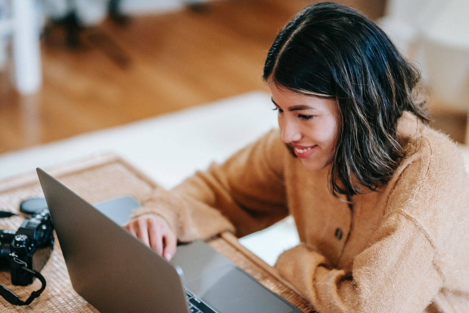 Mädchen sitzt lächelnd vor Laptop CV