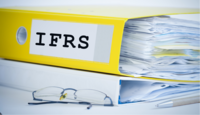 gelber Ordner mit Aufschrift "IFRS" und Brille 