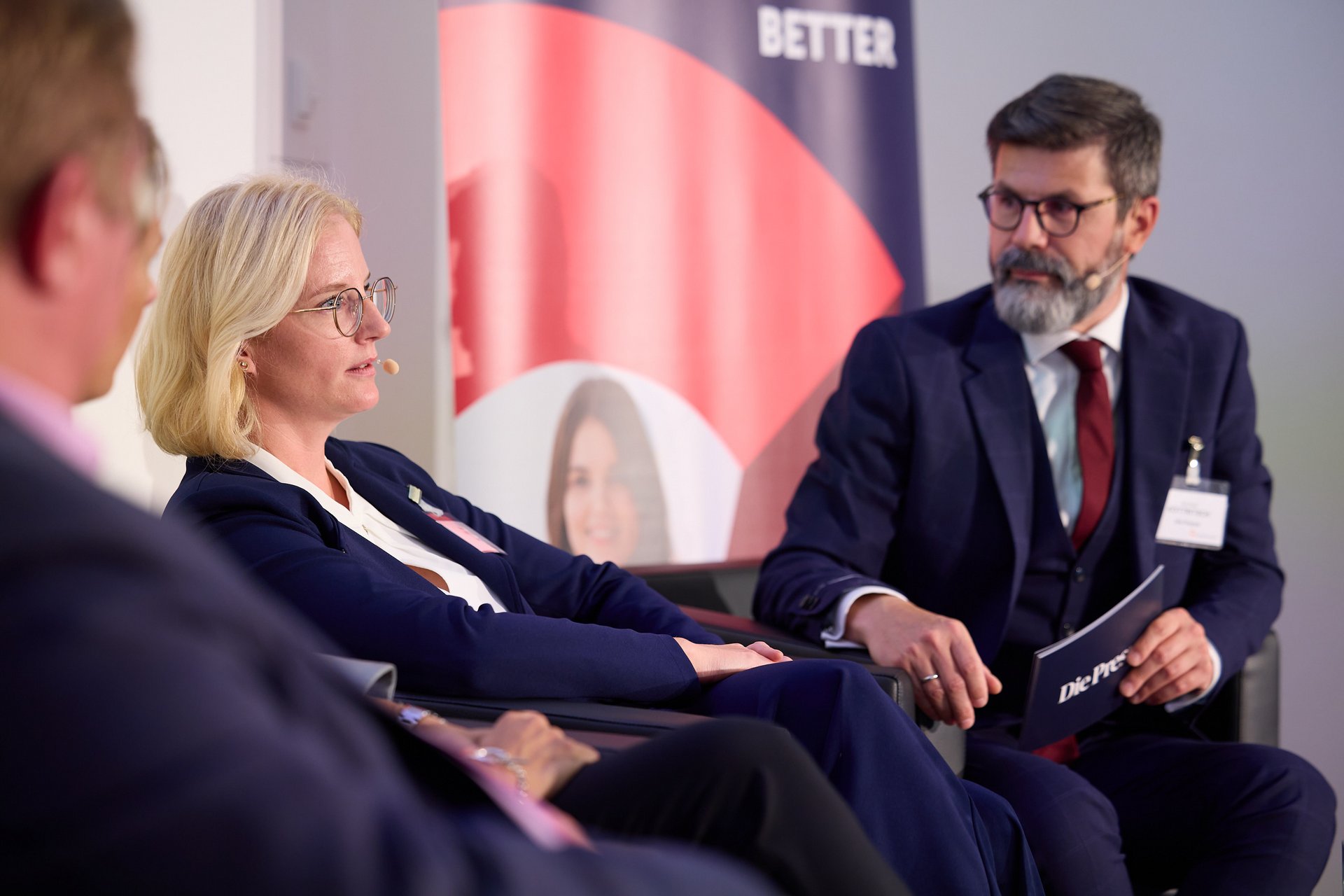 Gespräch zwischen einem Herrn in Anzug und blonder Dame in Anzug