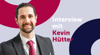 Mann im Anzug lächelt, Interview mit Kevin Hütter