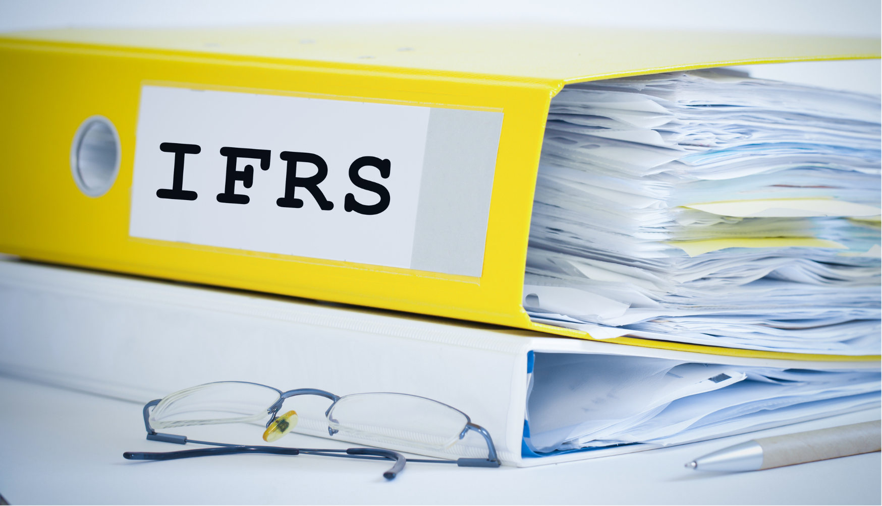 gelber Ordner mit Aufschrift "IFRS" und Brille 